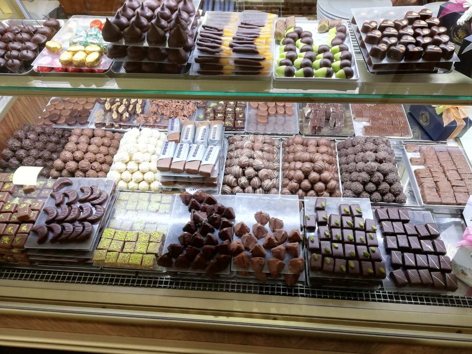 Truffes, pralinés et Adoua alignés dans la vitrine à chocolats de la Confiserie Baechler.